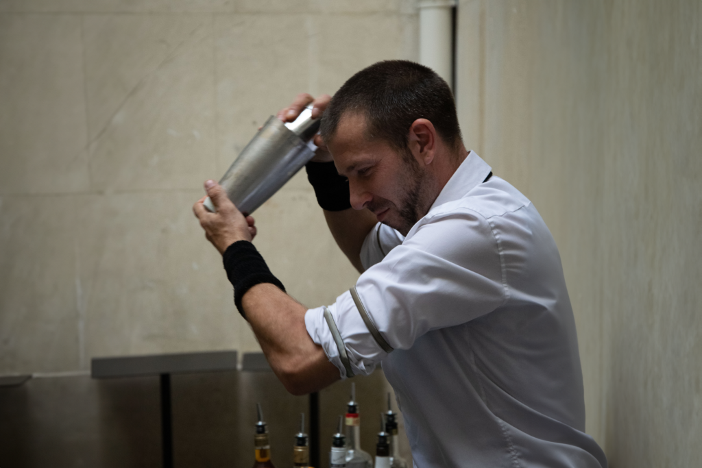 barman mixologue qui shake un cocktail